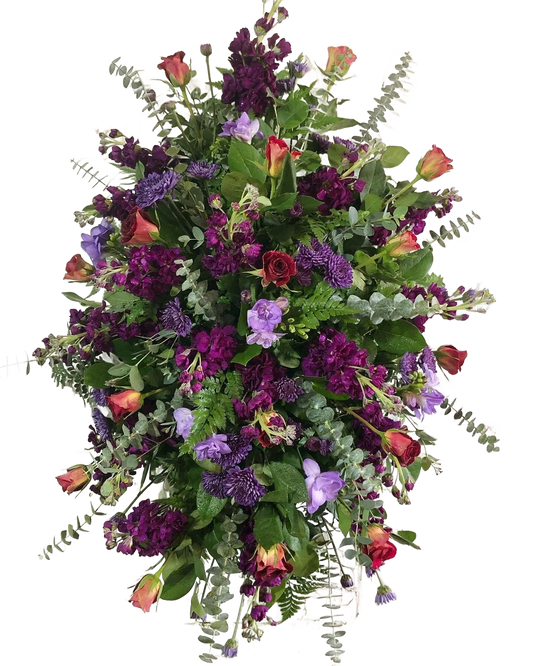 Colorful floral standing spray with purple stock, red roses, eucalyptus, and greenery with other flowers