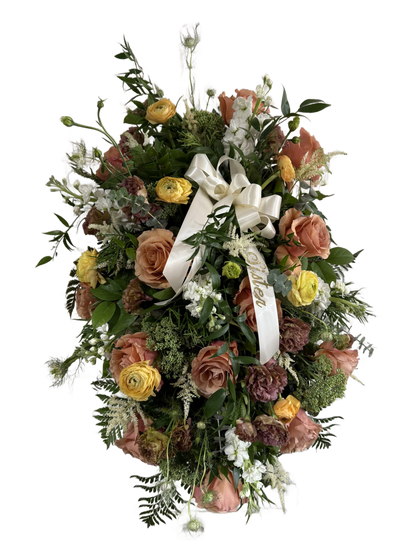 standing spray with copper, yellow, and green flowers with a white ribbon reading "sister" 