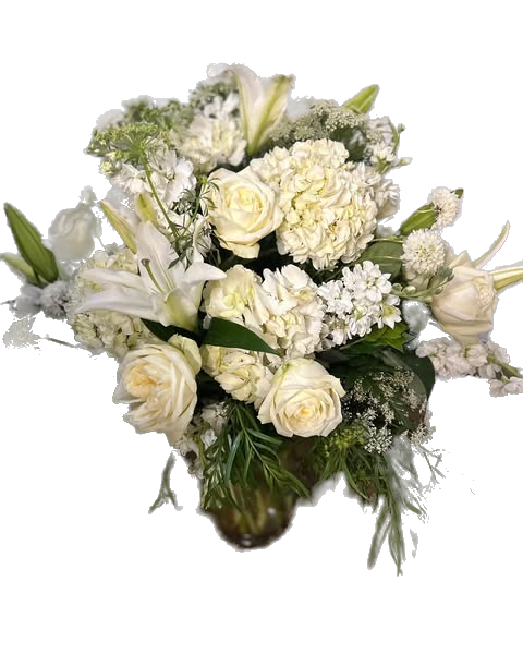 Bouquet of white flowers with roses, hydrangea, lilies, stock, and greenery in a clear vase 