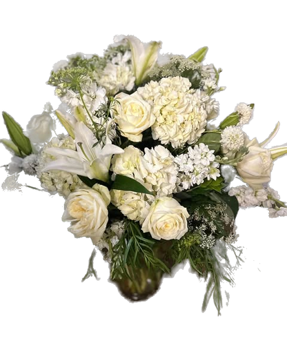 Bouquet of white flowers with roses, hydrangea, lilies, stock, and greenery in a clear vase 
