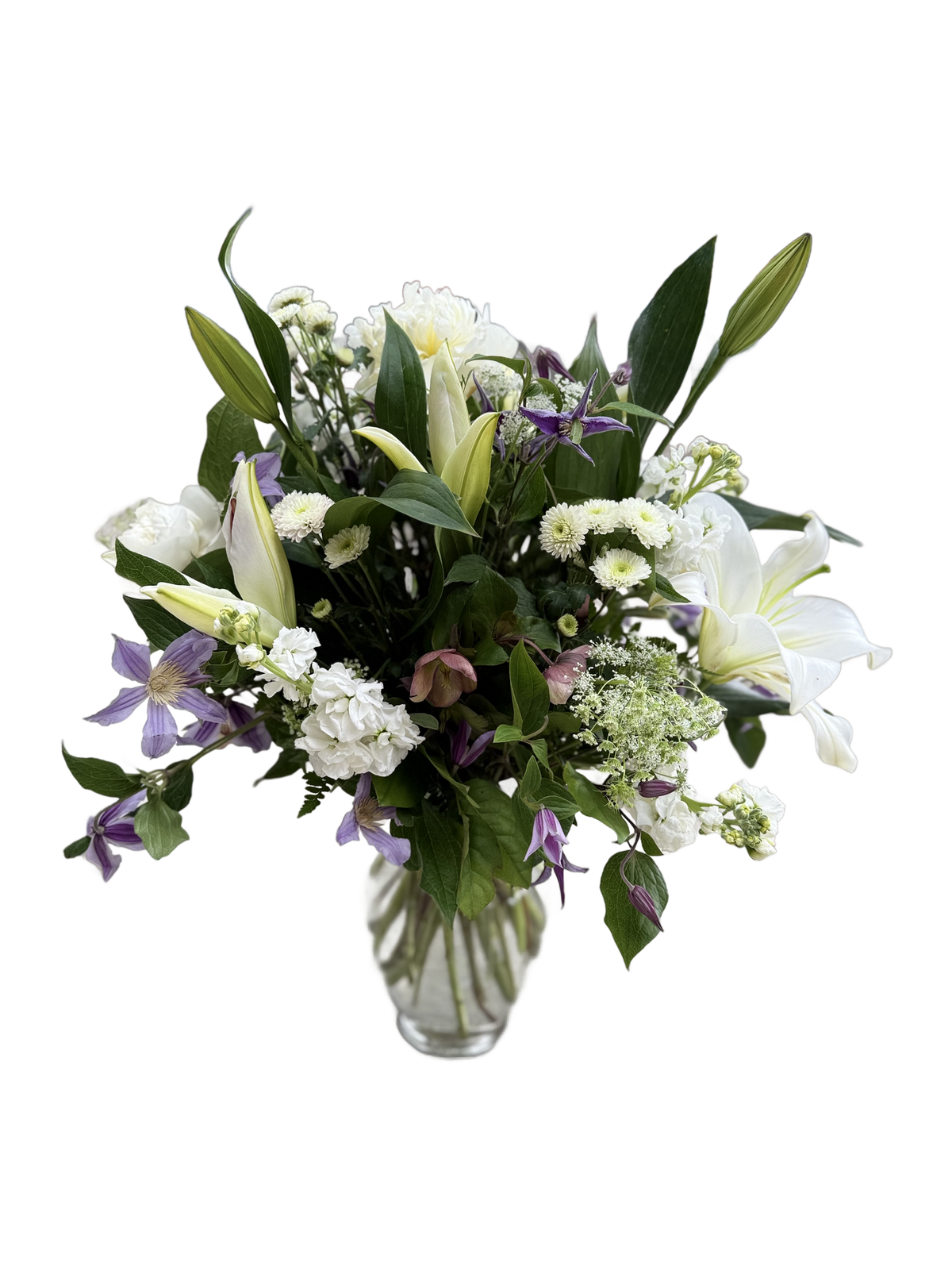 Bouquet of white lilies, purple clematis, and other white flowers in a clear vase