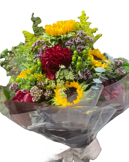 Bouquet of flowers with yellow sunflowers, red peonies, and green hypericum, wrapped in clear plastic and brown paper 